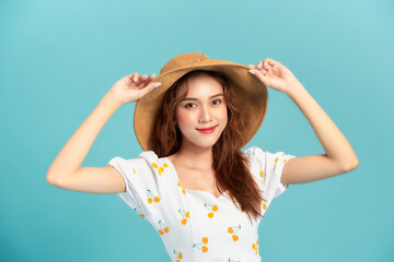 Obraz na płótnie Canvas Image of fashionable asian woman 20s smiling and touching straw hat on head isolated over blue background