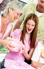 A girl happily receiving her birthday present from her mother while the others watching