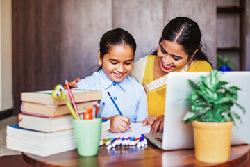 Indian girl getting coaching in her studies, learning at home with her female teacher