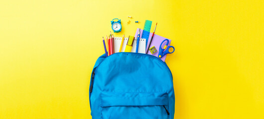School bag. Backpack with supplies for school on yellow background. Copy space for text