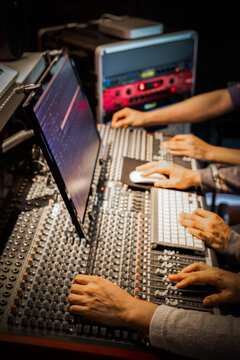 engineer team hands working on digital mixing console and studio equipment in recording, broadcasting studio. post production concept