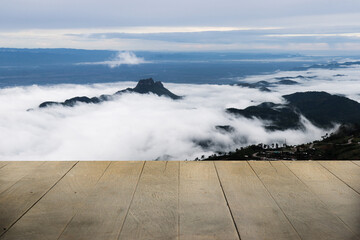 Wooden terrace with space for placing items or advertising media, with a background of misty mountains on the mountains.