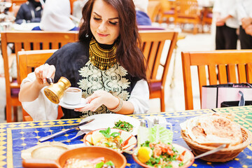 Young caucasian woman traveling in Turkey, drinking turkish coffee and eating traditional food in a outdoor cafe
