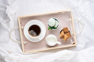 Breakfast tray, morning coffee with sweets on white bedding, top view.