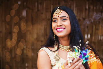 Beautiful Indian woman in traditional clothes and jewelry praying and offering flowers and incense...