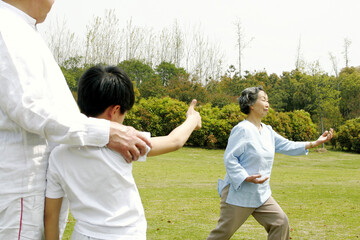 A boy giving his grandmother a thumb up for performing a good tai chi technique in the park