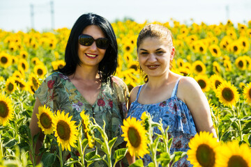 Friends women posing in sunflower field