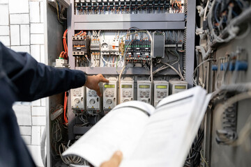 Worker engineer checks electrician measurements with tester multimeter for industrial production