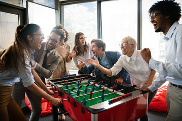 Employees playing table soccer indoor game in the office during break time