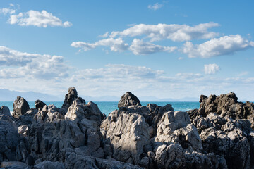 Jagged rock formations at Cefal&ugrave;, Italy, with rugged cliffs rising from calm water under a blue sky
