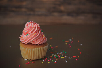 Delicious pink cupcakes on old wooden background