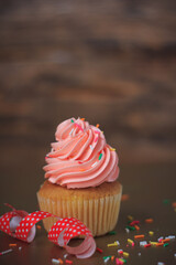 Delicious pink cupcakes on old wooden background