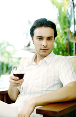 Man holding a glass of red wine while looking at the camera