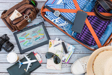 Above view of wooden table with travel, male accessories, luggage and personal items, camera, maps,...