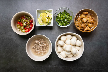 Fish ball, garlic cracklings with lard, mined pork, pickled chili, lime and coriander with spring onion various ingredients and condiment on table for noodles menu.