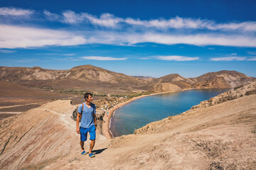 Fototapeta na wymiar Man climbing mountain above blue lagoon landscape.