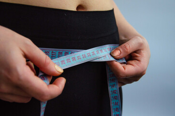 Young woman measures the volume of the hips and waist background

