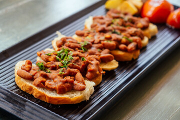 delicious red bean on the bread with potato and tomato on rectangular black plate vegan organic meal