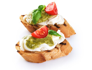 Bruschetta with mozzarella cheese, pesto, tomatoes and basil isolated on white background.