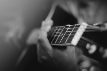 Closeup of a man playing the guitar strings in monochrome