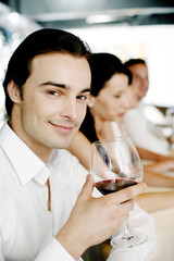Man holding a glass of red wine while smiling at the camera