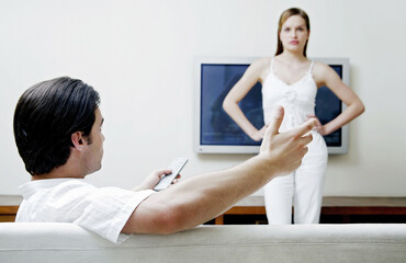 Naklejka premium Woman standing in front of the television blocking her boyfriend