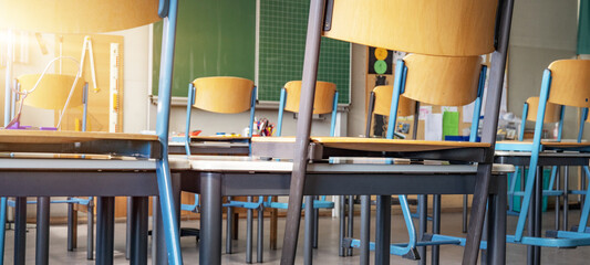 CORONAVIRUS - School closed - Empty classroom with high chairs and empty blackboard
 - obrazy, fototapety, plakaty