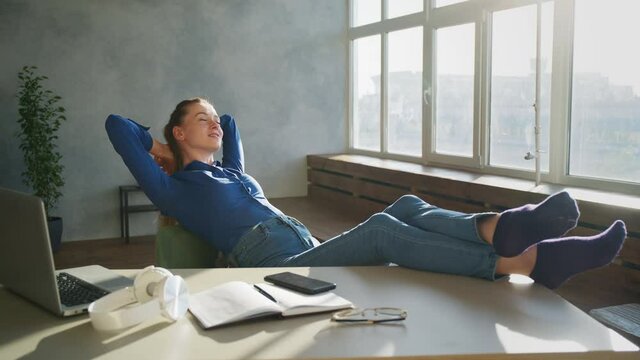 Calm smiling businesswoman relaxing at comfortable office chair hands behind head, happy woman resting in office satisfied after work done, enjoying break with eyes closed, peace of mind, no stress