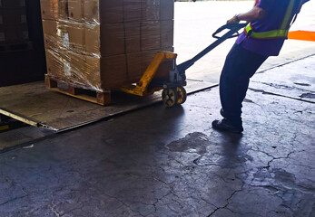 Worker unloading shipment carton boxes and goods on wooden pallet by forklift  from container truck to warehouse cargo storage in logistics and transportation industrial 