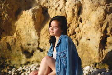 portrait of a woman in a denim jacket on a background of yellow rock