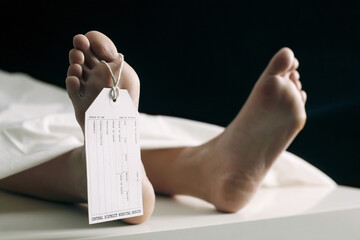 Toe tag hanging on woman lying on table in morgue