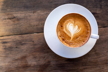 top view of White coffee cup with heart shape latte art on wood table at cafe with copy space