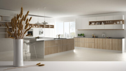 White table top or shelf with straws, dry plants, ornament, ears, sheaf, branch in vase, over wooden and white kitchen with accessories, modern minimal interior design