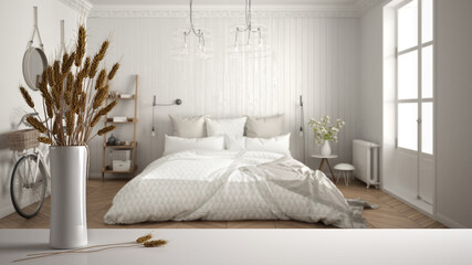 White table top or shelf with straws, dry plants, ornament, ears, sheaf, branch in vase, over classic white bedroom with double bed, modern minimal interior design