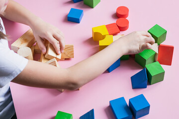 Little kid plays assemble with wooden cubes constructor. Education concept for children learning. Children's toys