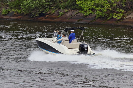 Modern open bowrider motor boat with 150 hp powerful outboard motor fast gliding on calm water with spray, side rear top view on summer day, powerboat active recreation, river watersports