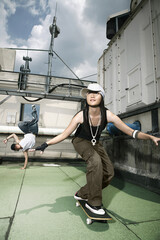 Young woman playing with skateboard, young man breakdancing in the background