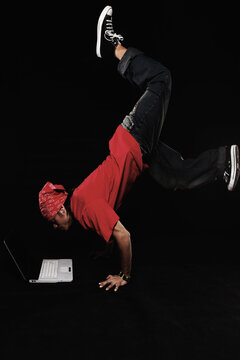 Young man in breakdance move using laptop