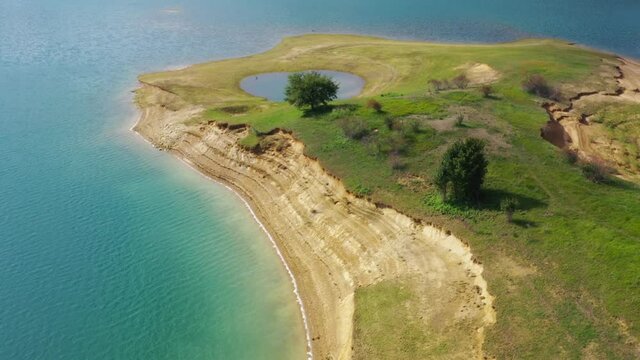 Island with flooded pond in Rama Lake Bosnia and Herzegovina on a calm sunny day, Aerial dolly out shot