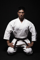 Man in karate uniform kneeling down © ImageHit