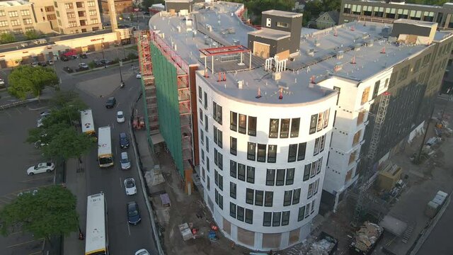 aerial view brand new building still in construction in the corner of a crowdy street during golden hour