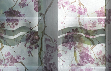A window with violet flower curtains in late evening light