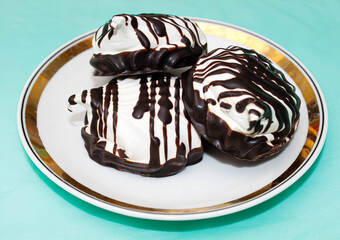Delicious white Marshmallows poured with dark chocolate lies on a saucer.