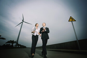 Businessman and businesswoman talking while walking on the road