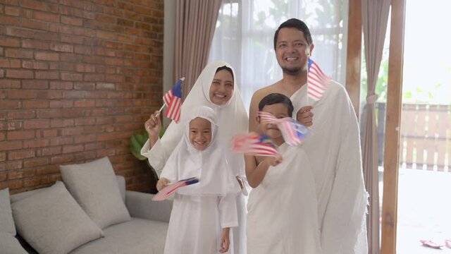 happy muslim umrah and hajj with family holding malaysia flag
