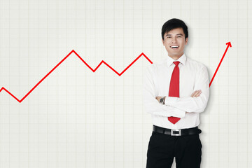 Businessman standing in front of line graph with his arms folded