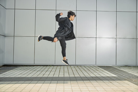 Handsome guy jumping against the wall outdoors