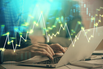 Double exposure of market chart with man working on computer on background. Concept of financial analysis.