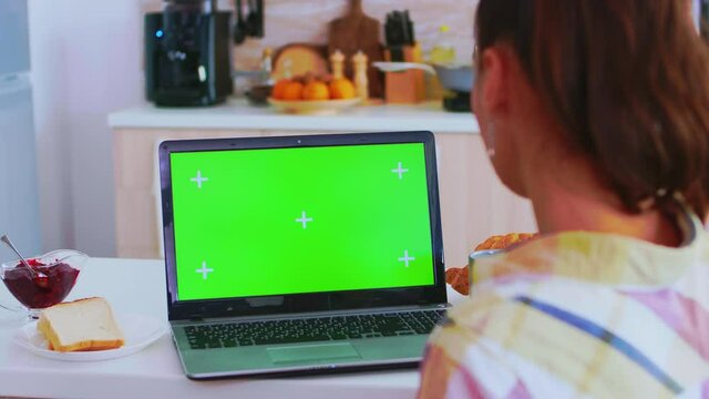 Working on tablet pc with green screen in kitchen during breakfast. Green screen chroma mock up isolated mockup background ready to be replaced with your text, logo or advertisement. Using internet