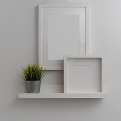 Modern home interior design with mock-up frames and plant pot above white shelf on white wall